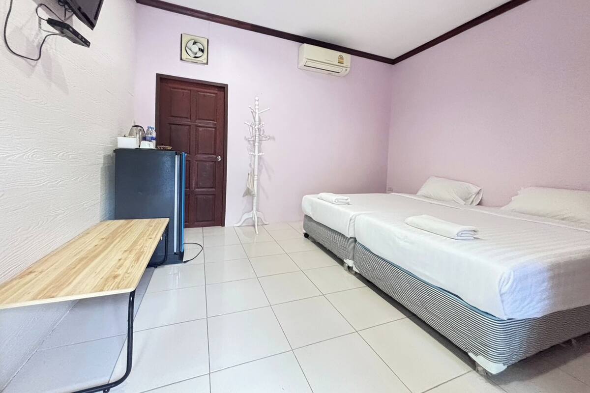 A room with a bed, a desk, a chair, an air conditioner, and a TV mounted on the wall.