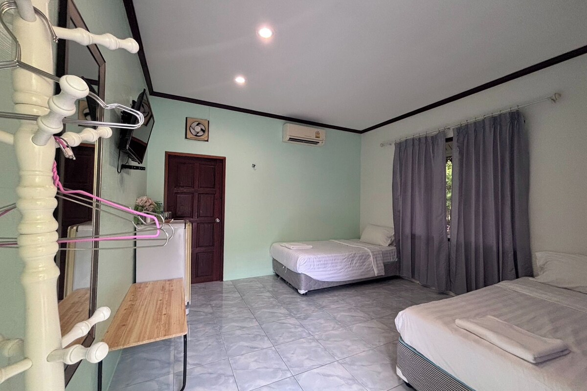 Habitación con cama, escritorio y espejo. Se observa una puerta y una ventana con cortinas.