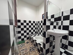 A bathroom with a checkered black and white tile pattern, a white sink, and a bathtub. - Aioun At Amphawa (Amphawa)
