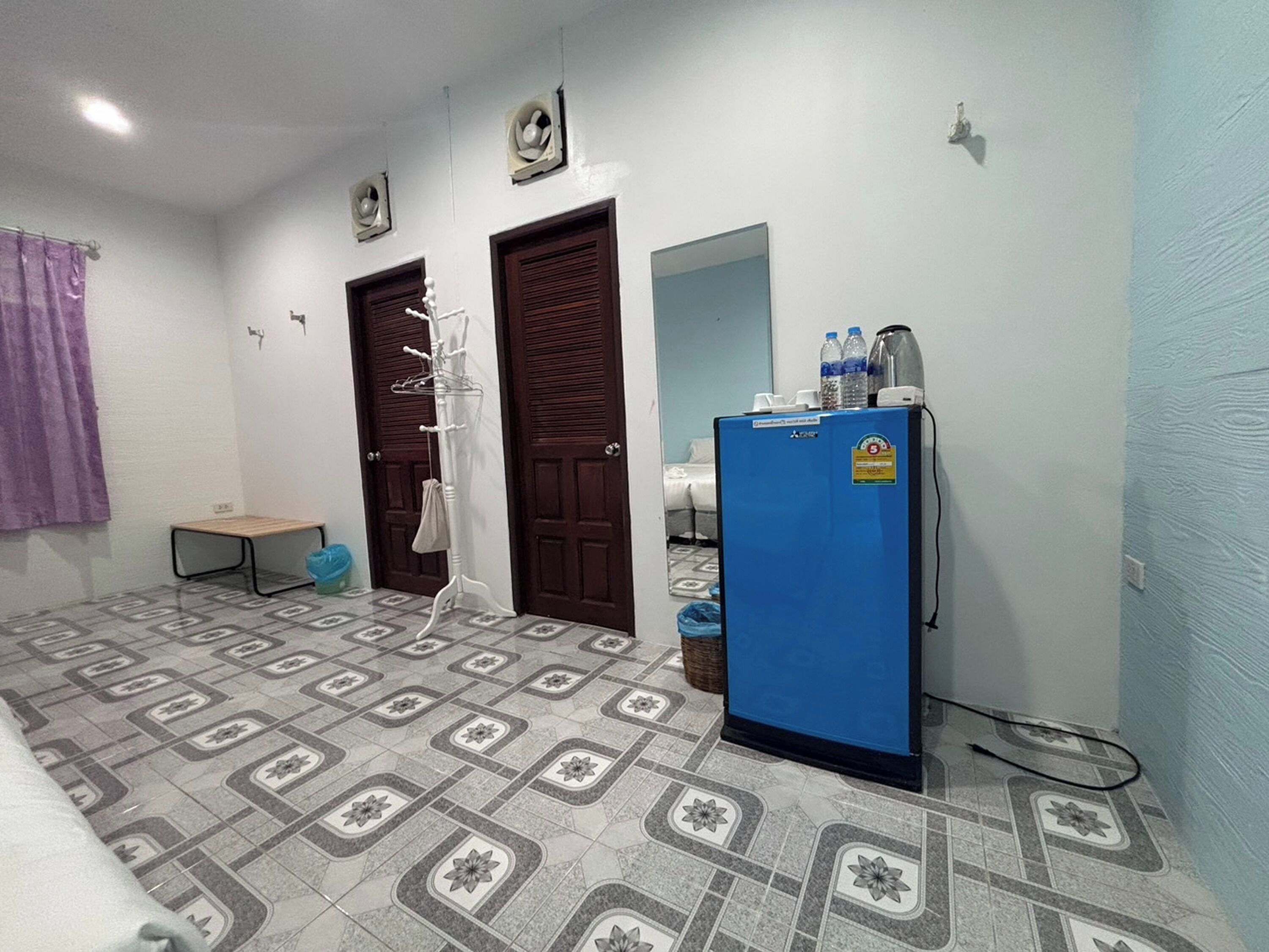 Una habitación con baldosas de diseño en el suelo, un refrigerador azul, un perchero y dos puertas.