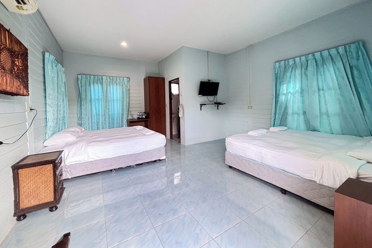 A hotel room with two beds, a TV, and a small desk.