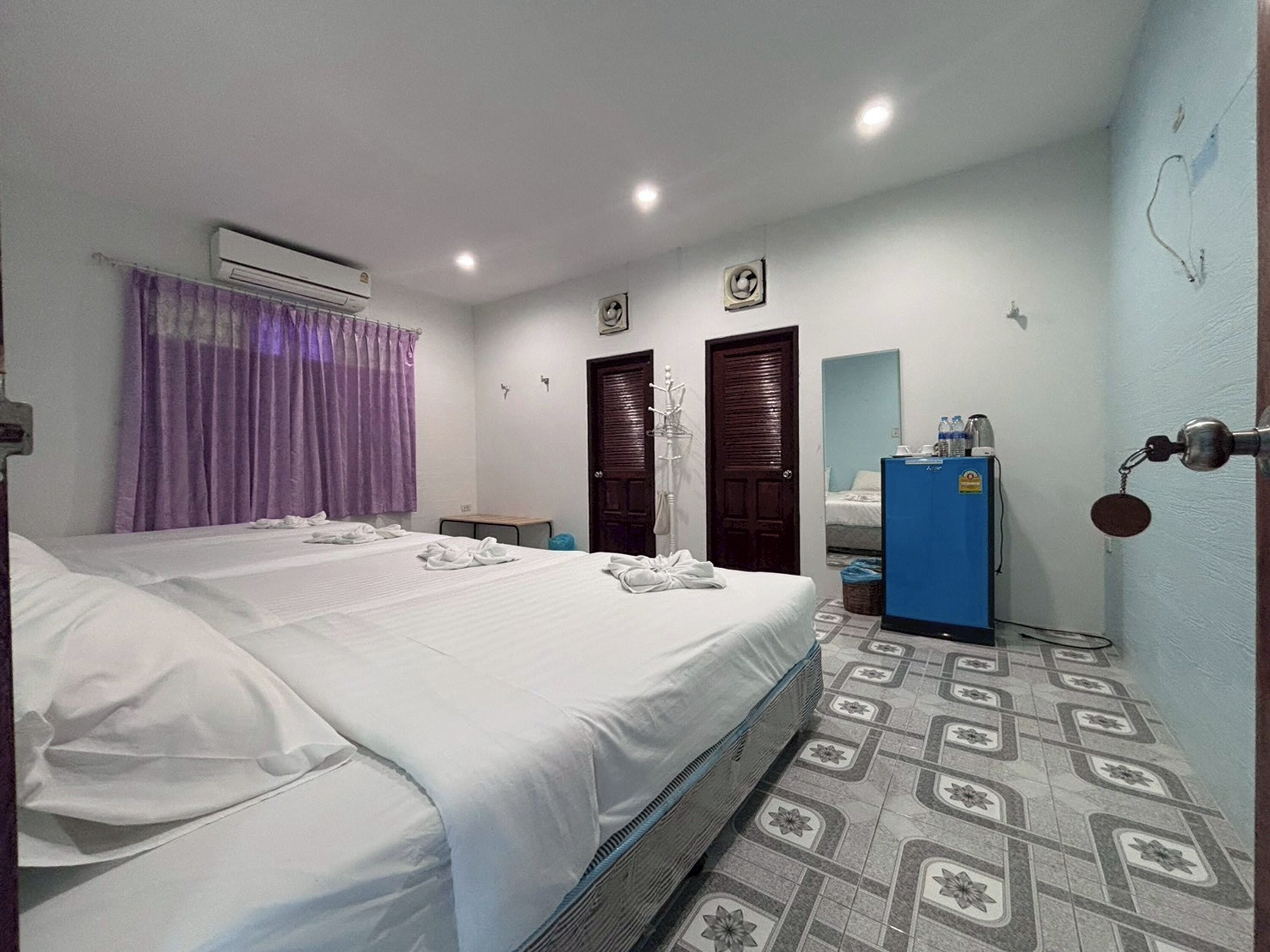 Een hotelkamer met een bed, een bureau, een airconditioning, een spiegel en een blauwe kast.