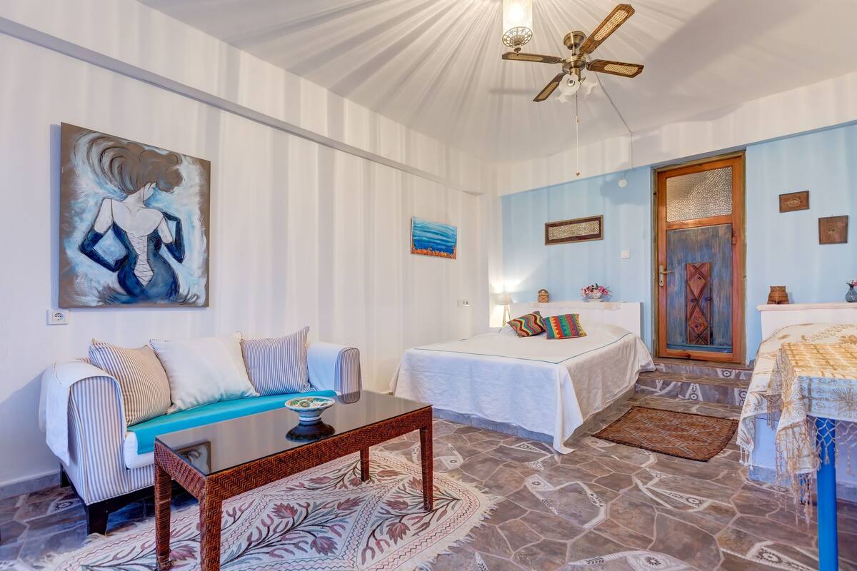 Ein Zimmer mit einem Bett, einem Sofa, einem Couchtisch und einem Bild an der Wand.