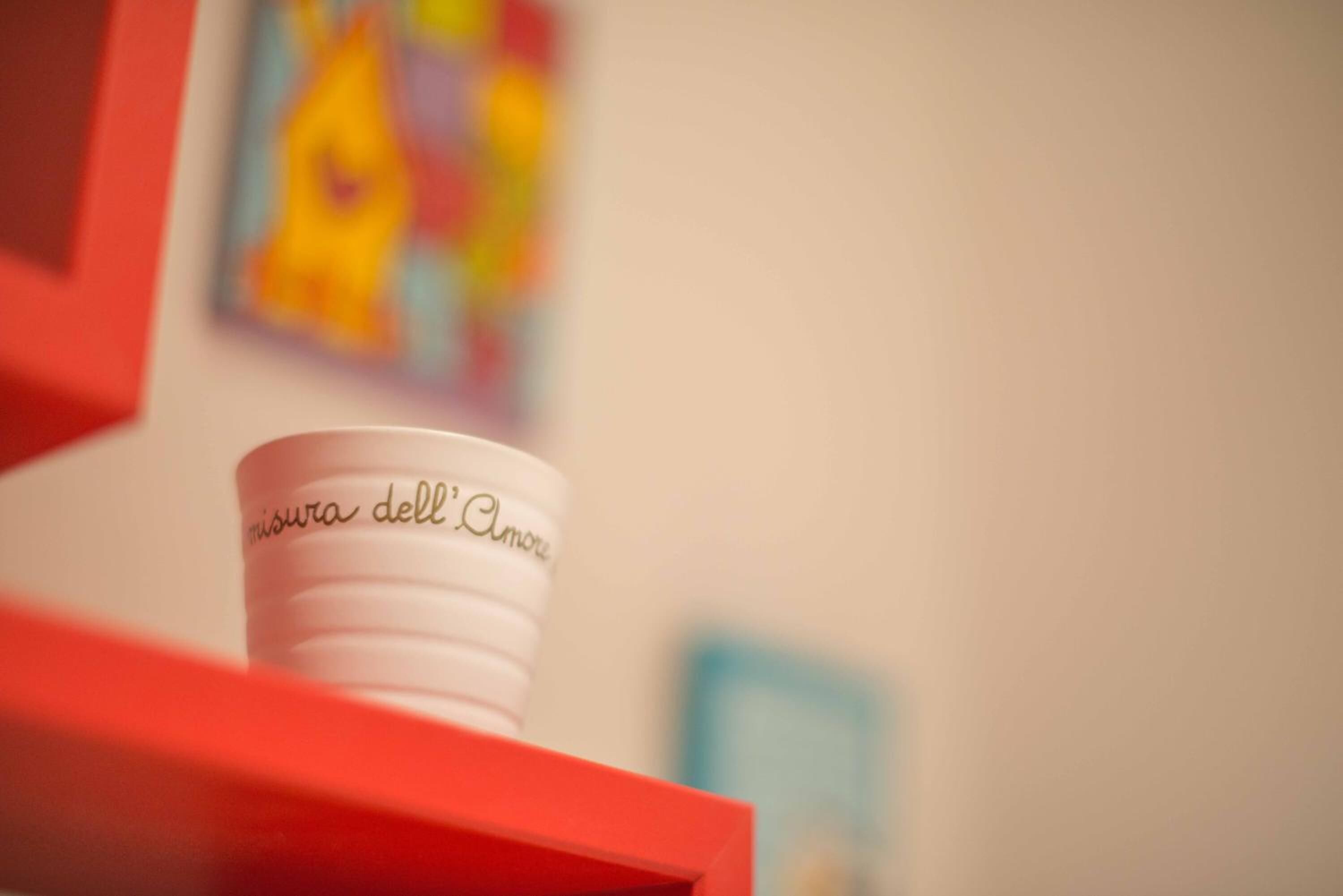 A white mug with text on it placed on a red surface.