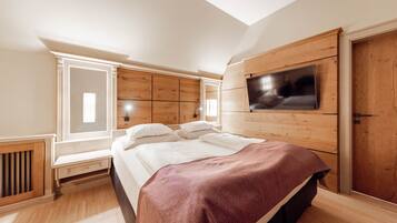 Un dormitorio con cama, televisor montado en la pared y ventana que proporciona luz natural.