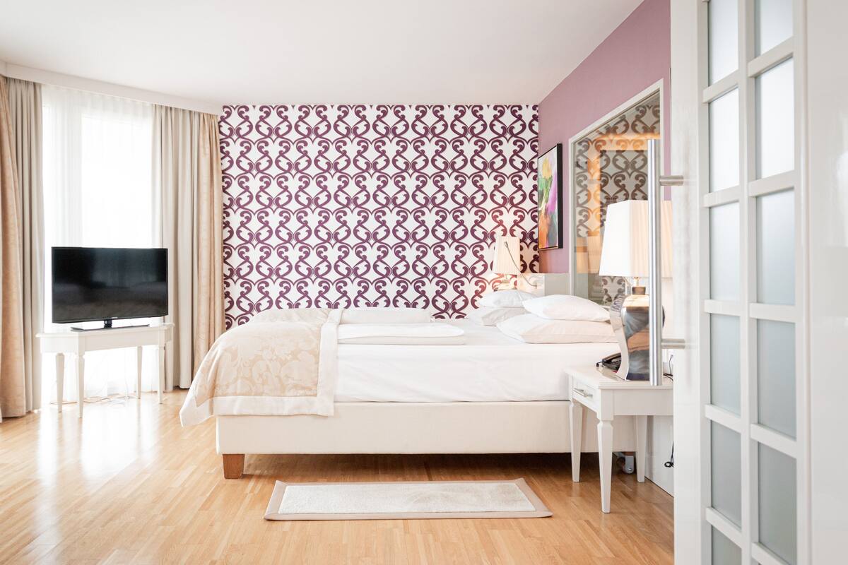 Ein modernes Hotelzimmer mit einem großen Bett, einem Fernseher, einem Nachttisch und einer Wand mit Musterung.