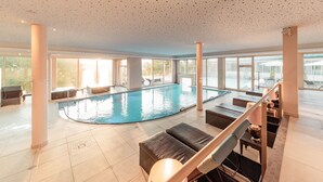 An indoor swimming pool with lounge chairs and a staircase.