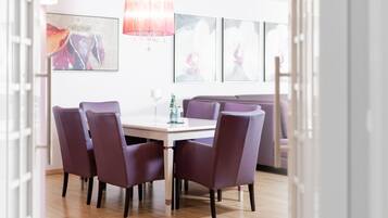 Ein Essbereich mit einem weißen Tisch, violetten Stühlen und einer Kristallleuchter.