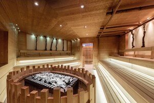 Un área de spa con bancos de madera, una chimenea central y techo de madera.