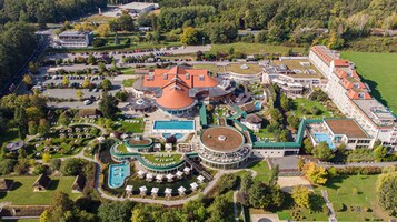 Vista aérea de un complejo turístico con un edificio central, una piscina y varias villas para huéspedes.