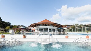 A pool area with a central water feature, a covered seating area, and a building with a red roof.