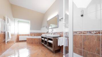 Un baño moderno con un espejo grande, una bañera y una zona de ducha.