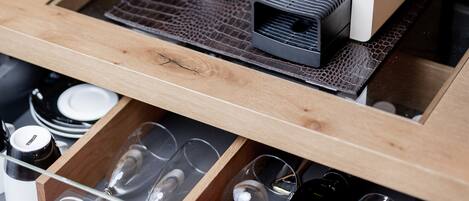 A drawer with wine glasses and bottles, a wine cooler, and a coffee machine.