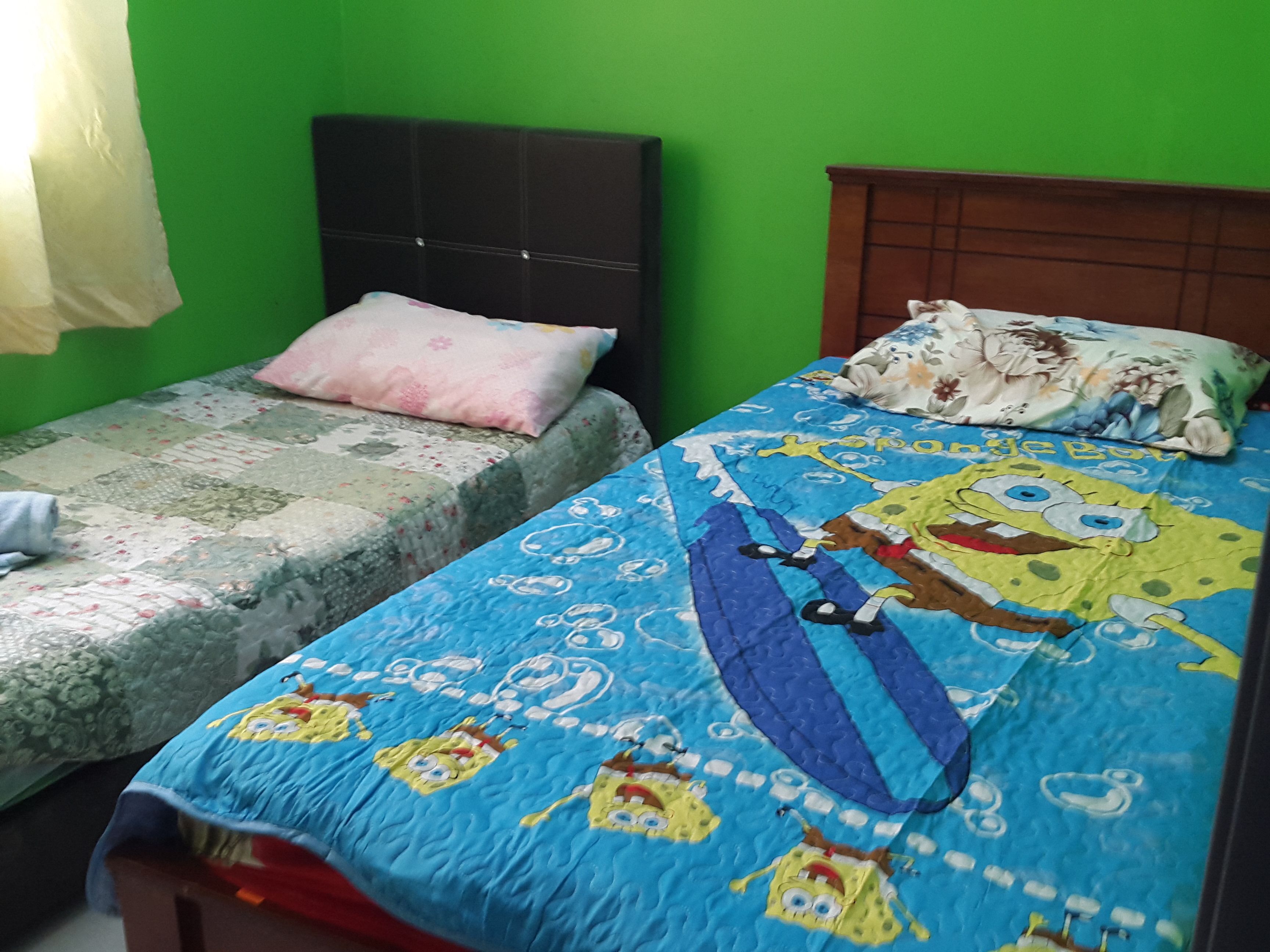A room with two beds, one with a floral bedspread and the other with a SpongeBob-themed bedspread.