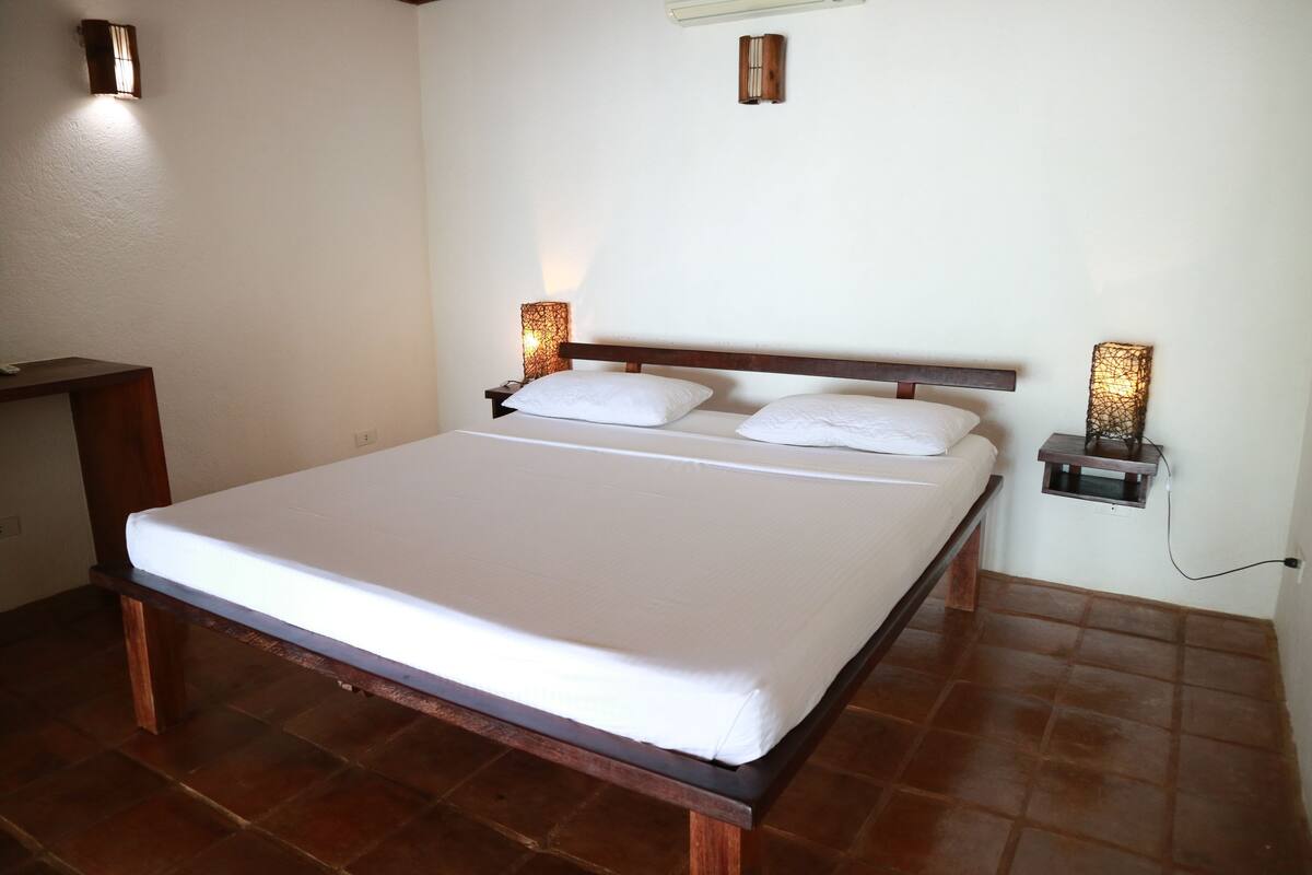 A neatly made bed with a wooden headboard and two bedside lamps.