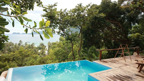 A swimming pool with a wooden deck and a view of the sea. - El Nido Overlooking Resort (El Nido)