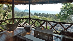 A wooden deck with wicker furniture, overlooking a lush landscape and the sea. - El Nido Overlooking Resort (El Nido)