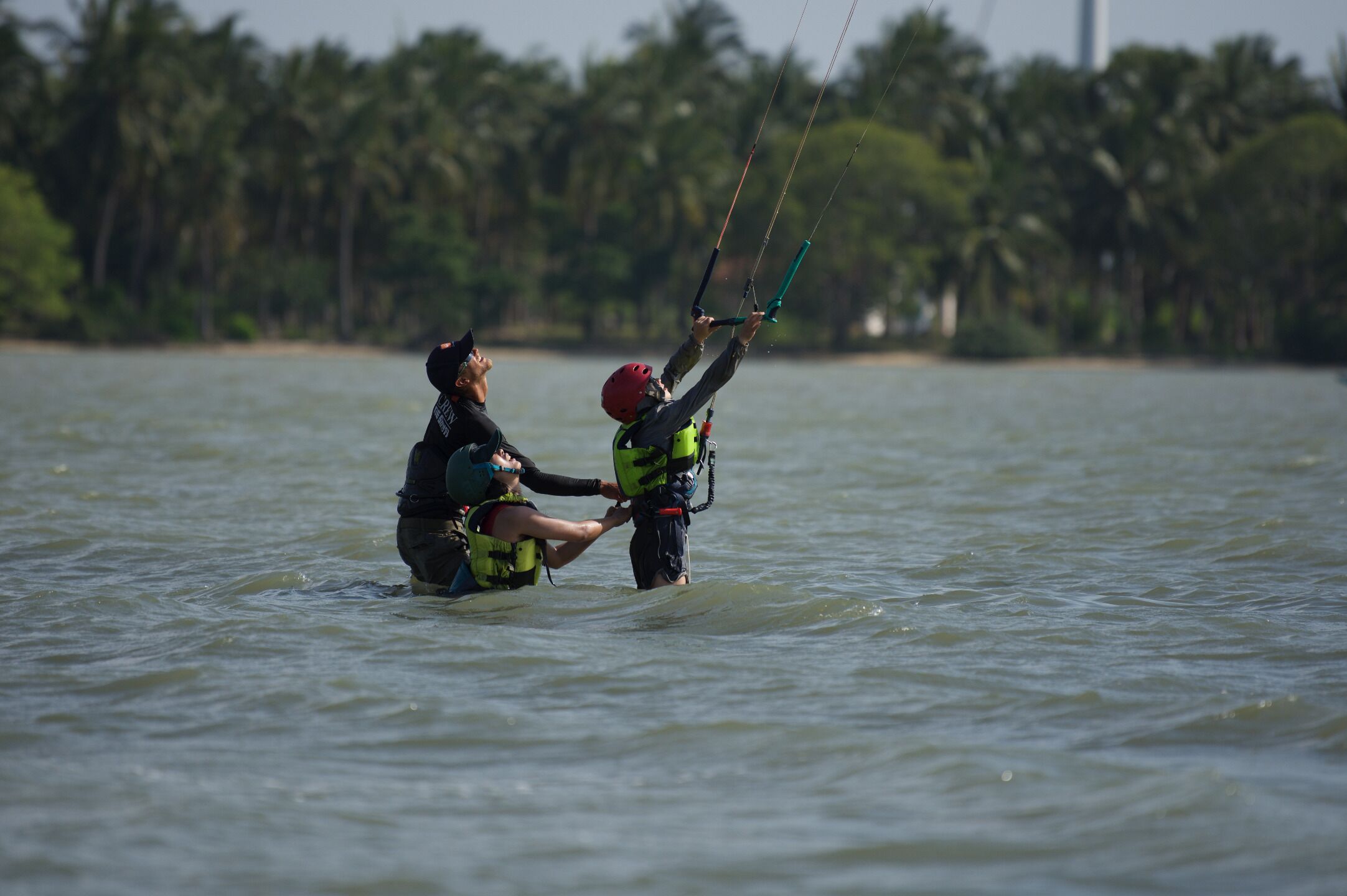 Una persona en el agua con una cometa, usando chaleco salvavidas y casco.