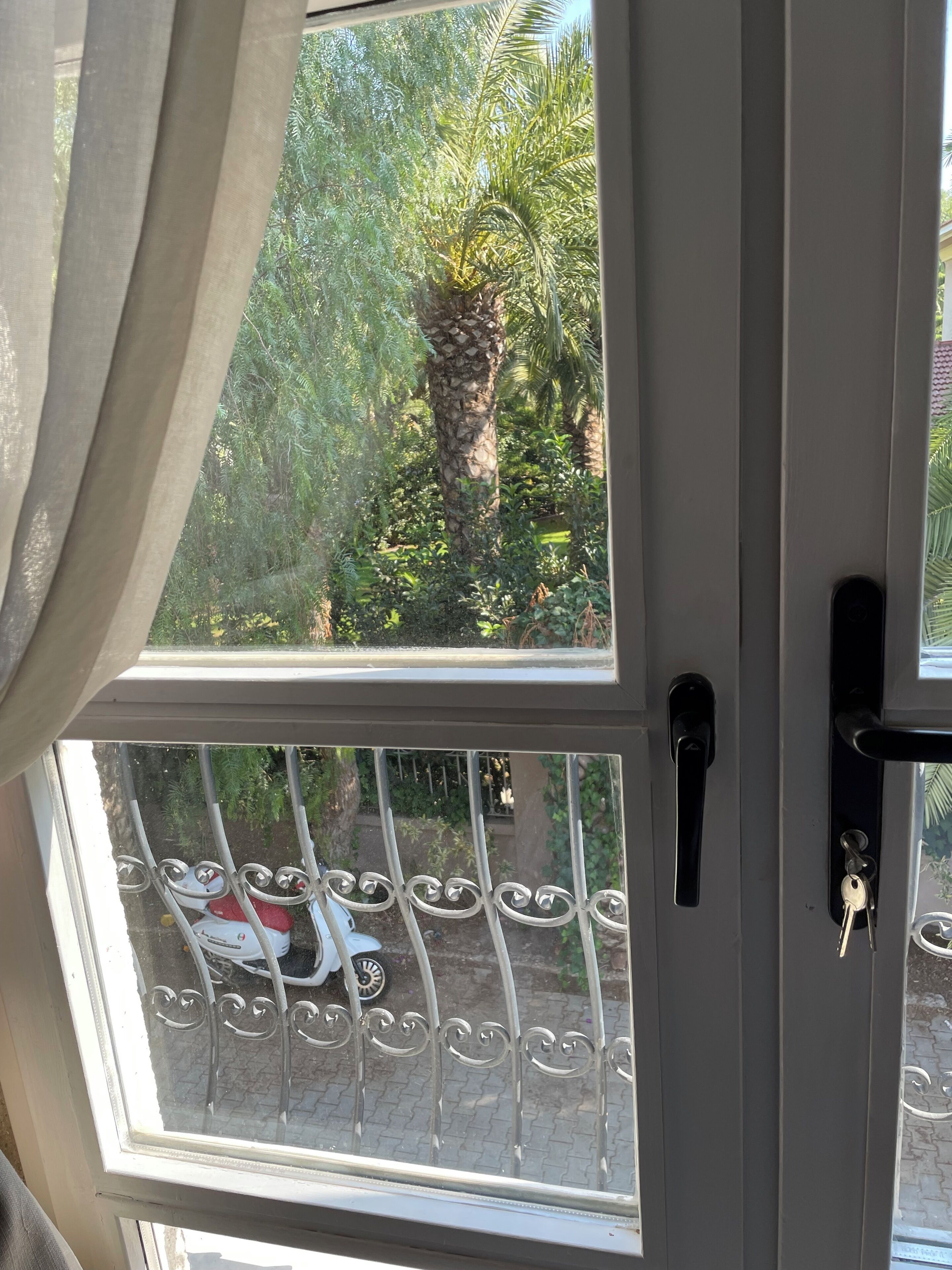 A view through a window with a metal gate and a door handle.