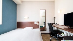 Een hotelkamer met een bed, een bureau met stoel, een televisie en een spiegel.