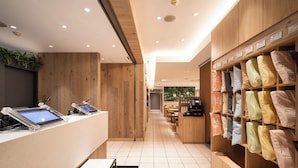Een moderne hotel lobby met houten lambrisering, een receptiebalie, een koffieapparaat en een presentatie van kussens.