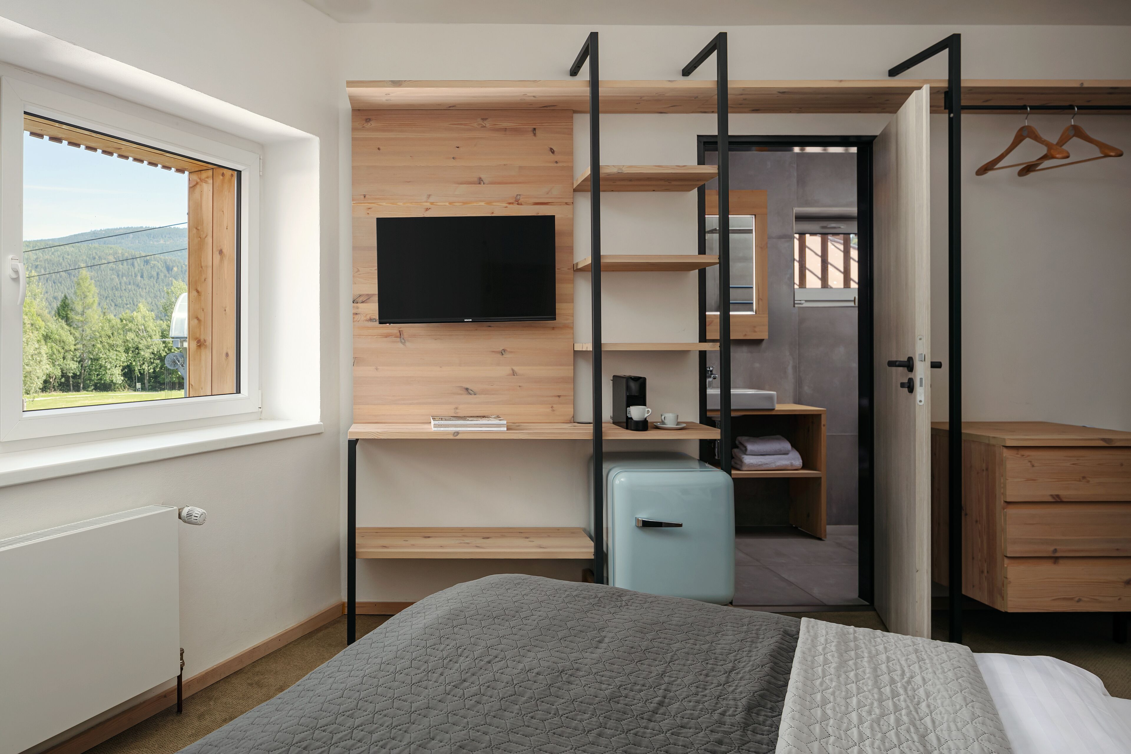 Ein gemütliches Schlafzimmer mit Bett, Fernseher an einer Holzwand, einem kleinen Kühlschrank und einem Kleiderschrank.