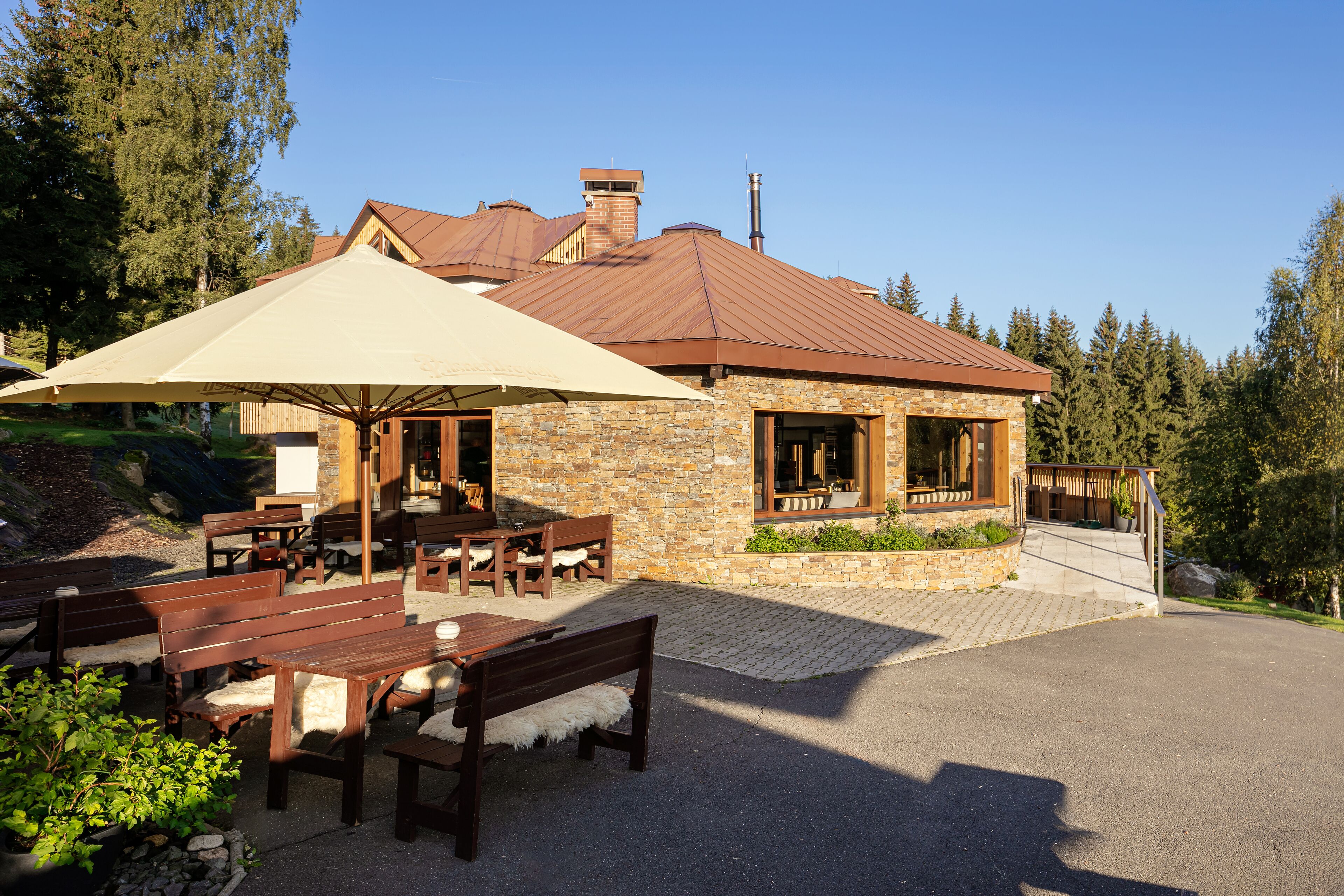A stone building with a metal roof, outdoor seating, and a covered patio area.