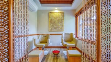 Traditional room with a wooden ceiling and walls featuring intricate lattice patterns, two cushioned chairs, and a decorative wall hanging.