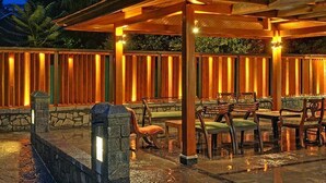 An outdoor patio area with wooden furniture and a stone wall. - Fortune Resort Heevan, Srinagar - Member ITC Hotels' Group (Srinagar)