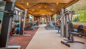 A gym with cardio machines, weightlifting equipment, and a large window offering a view of the outdoors. - Fortune Resort Heevan, Srinagar - Member ITC Hotels' Group (Srinagar)