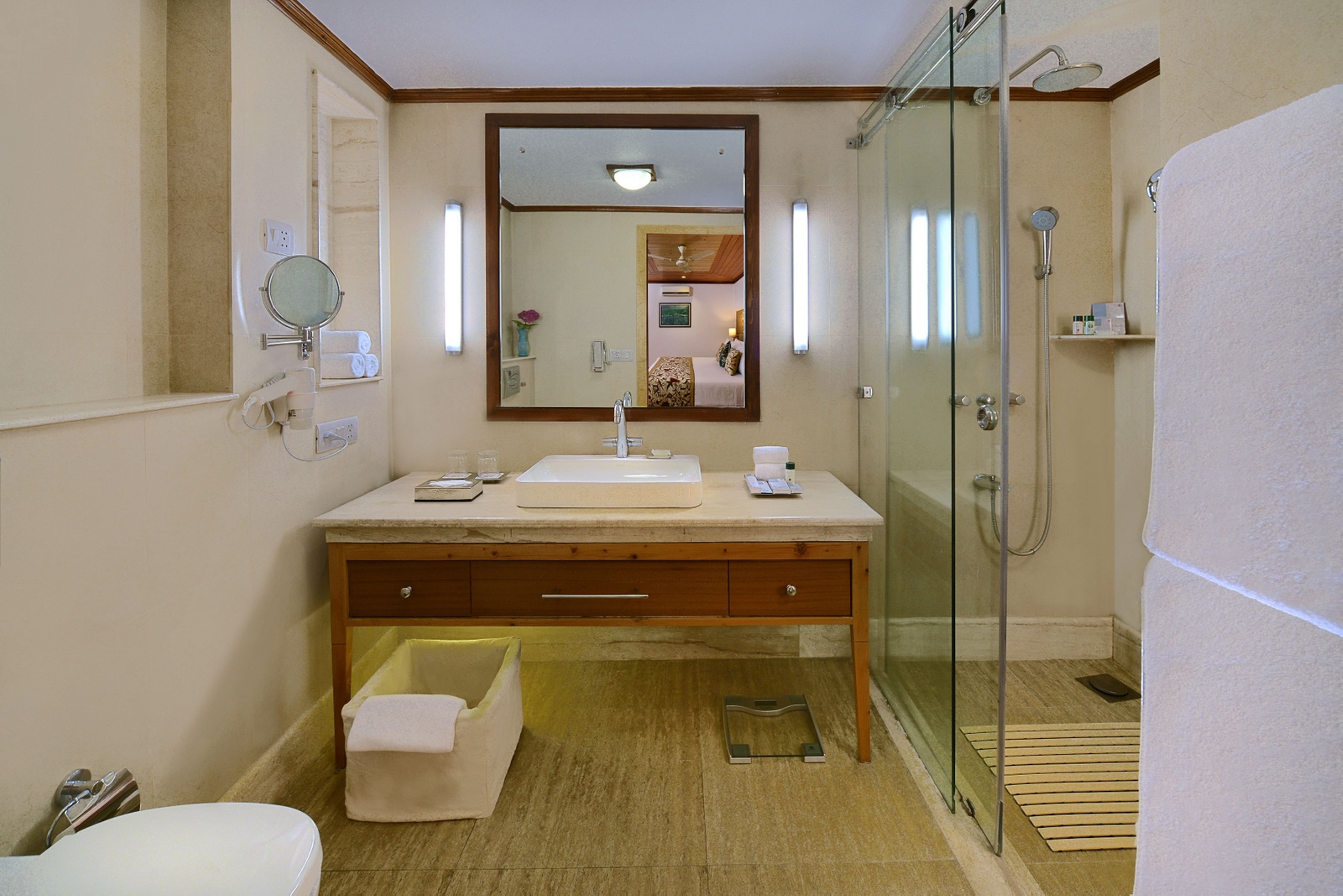 A bathroom with a glass-enclosed shower, a sink with a mirror above it, and a towel on the floor.
