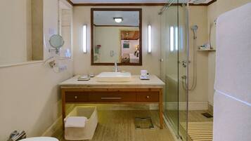 A bathroom with a glass-enclosed shower, a sink with a mirror above it, and a towel on the floor.