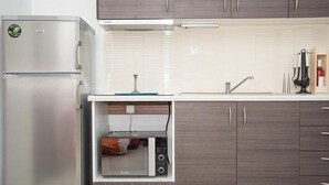 Una cucina compatta con forno a microonde integrato, frigorifero in acciaio inox e un moderno lavello.