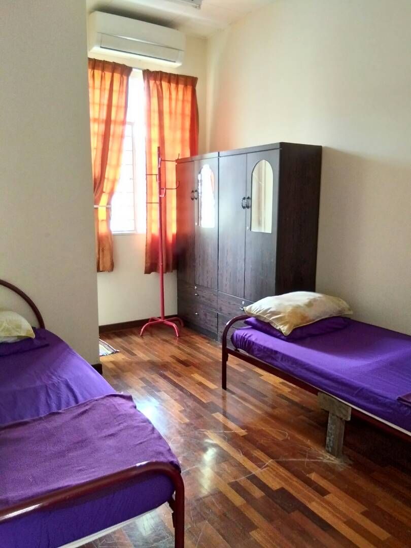 A room with two beds, a wardrobe, and a floor lamp.