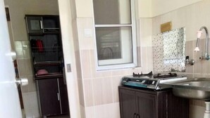 A kitchen with a gas stove, a sink, and a window. There is a door leading to another room. - Nadrah Putrajaya Homestay (Putrajaya)