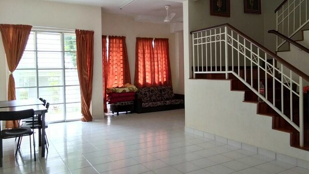 A spacious living area with a dining table and chairs, a sofa, and a staircase with a railing. - Nadrah Putrajaya Homestay (Putrajaya)