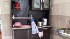 A compact kitchen with dark cabinetry, a stainless steel sink, and a tiled backsplash. - Nadrah Putrajaya Homestay (Putrajaya)