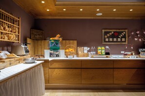 Een ontbijtbuffet met een koffieapparaat, een fruitmand en diverse ontbijtartikelen.
