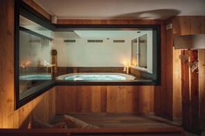 Une salle de spa en bois équipée d’un bain à remous, d’un miroir et d’un banc en bois.