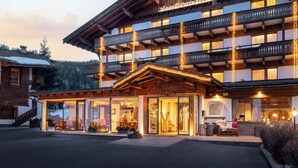 A multi-story hotel with a wooden facade, balconies, and a ground-level entrance with glass doors.