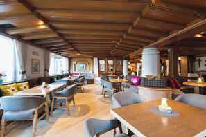 Um restaurante com vigas de madeira no teto, várias áreas de estar e vista para o exterior.