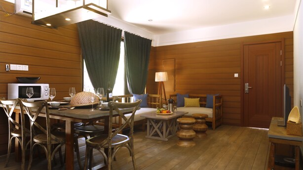 A cozy room with a wooden floor, a dining table with chairs, a sofa, a lamp, and a television. - shell villa apartel resort (Koror)