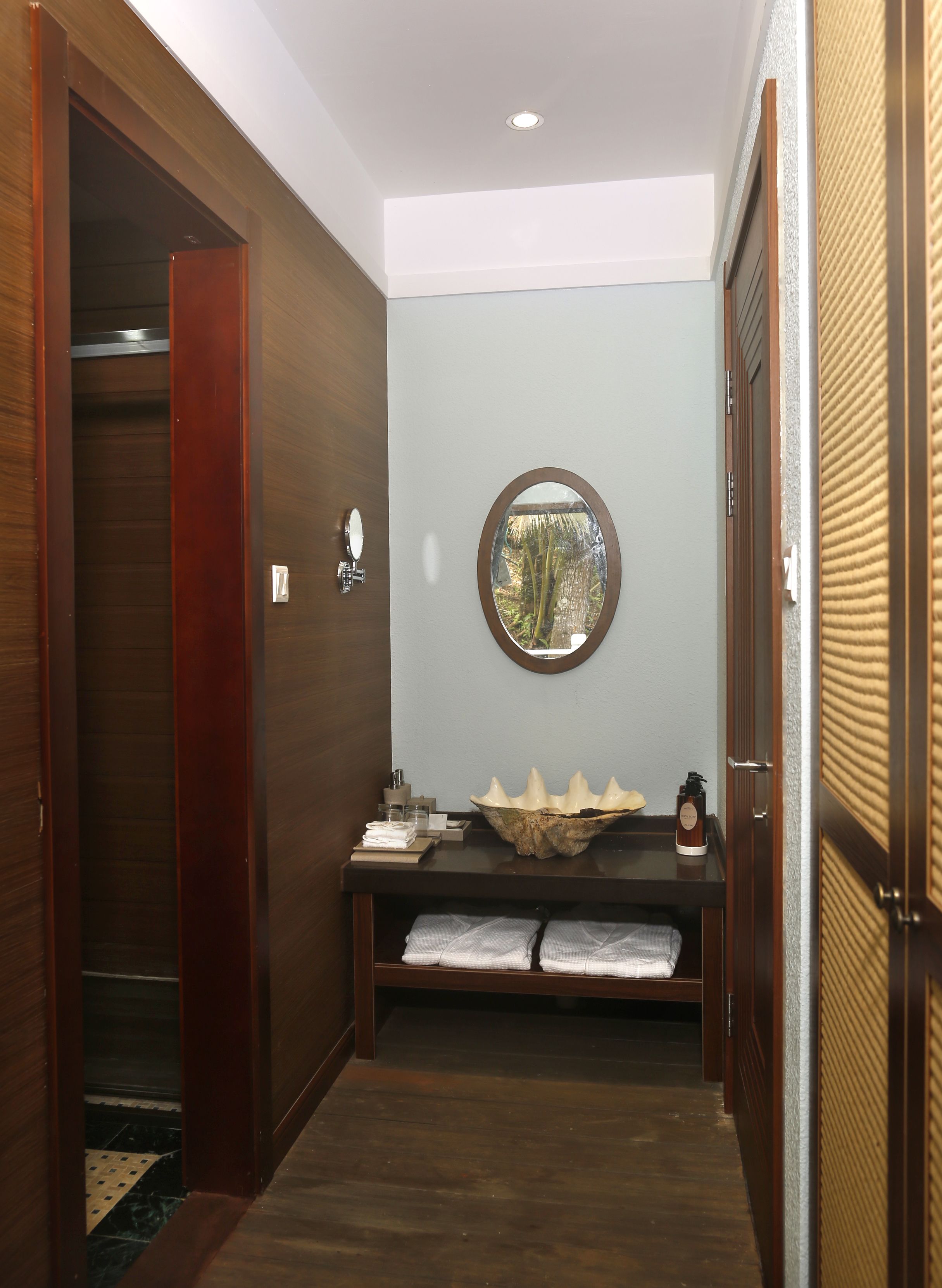 A hallway with a wooden door, a mirror, a bowl, and towels on a bench.