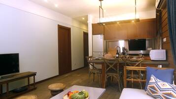 A compact living space with a dining area, kitchenette, and a seating area with a TV and a fruit basket.