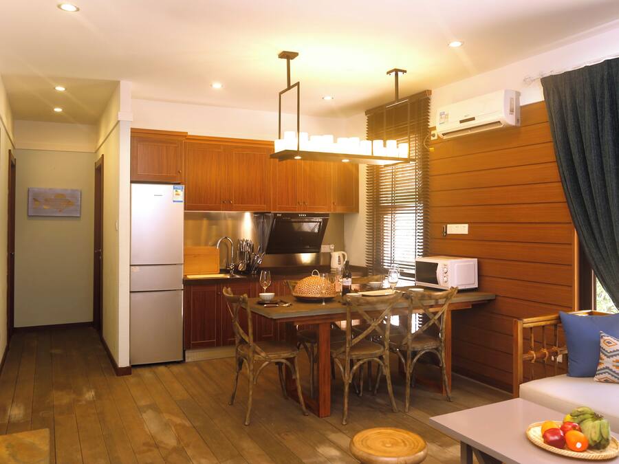 Una cocina compacta con armarios de madera, un refrigerador, un microondas y un comedor con mesa y sillas.