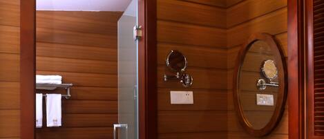 Un baño con paneles de madera, un inodoro, un lavabo con espejo y una zona de ducha.