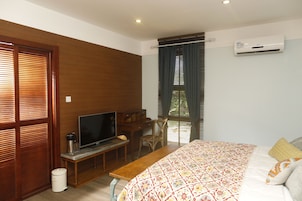 Un dormitorio con cama, televisor, escritorio y aire acondicionado.