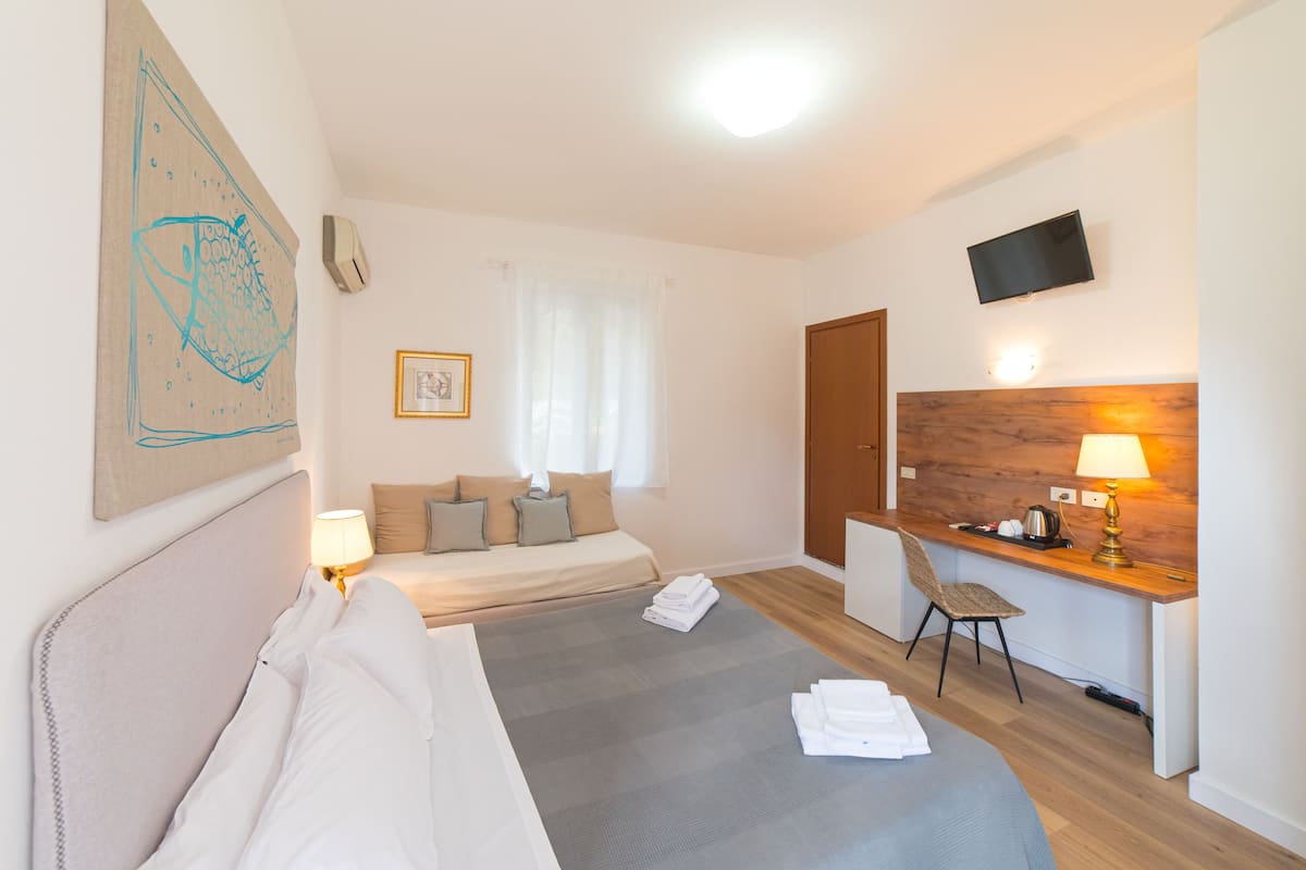 Una habitación de hotel con cama, escritorio, silla, televisor y un cuadro en la pared.