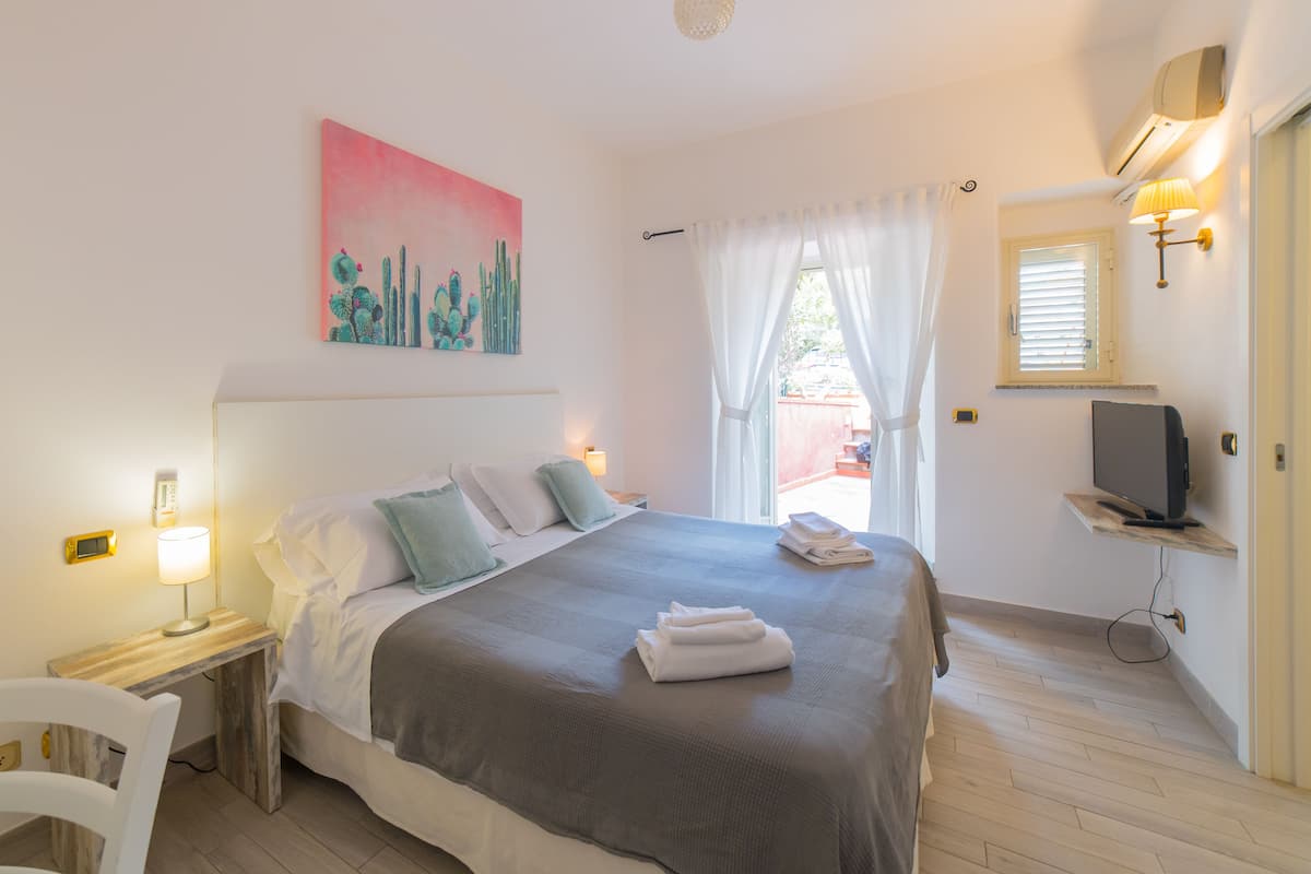 Un dormitorio con cama, mesitas de noche, televisor y un cuadro.
