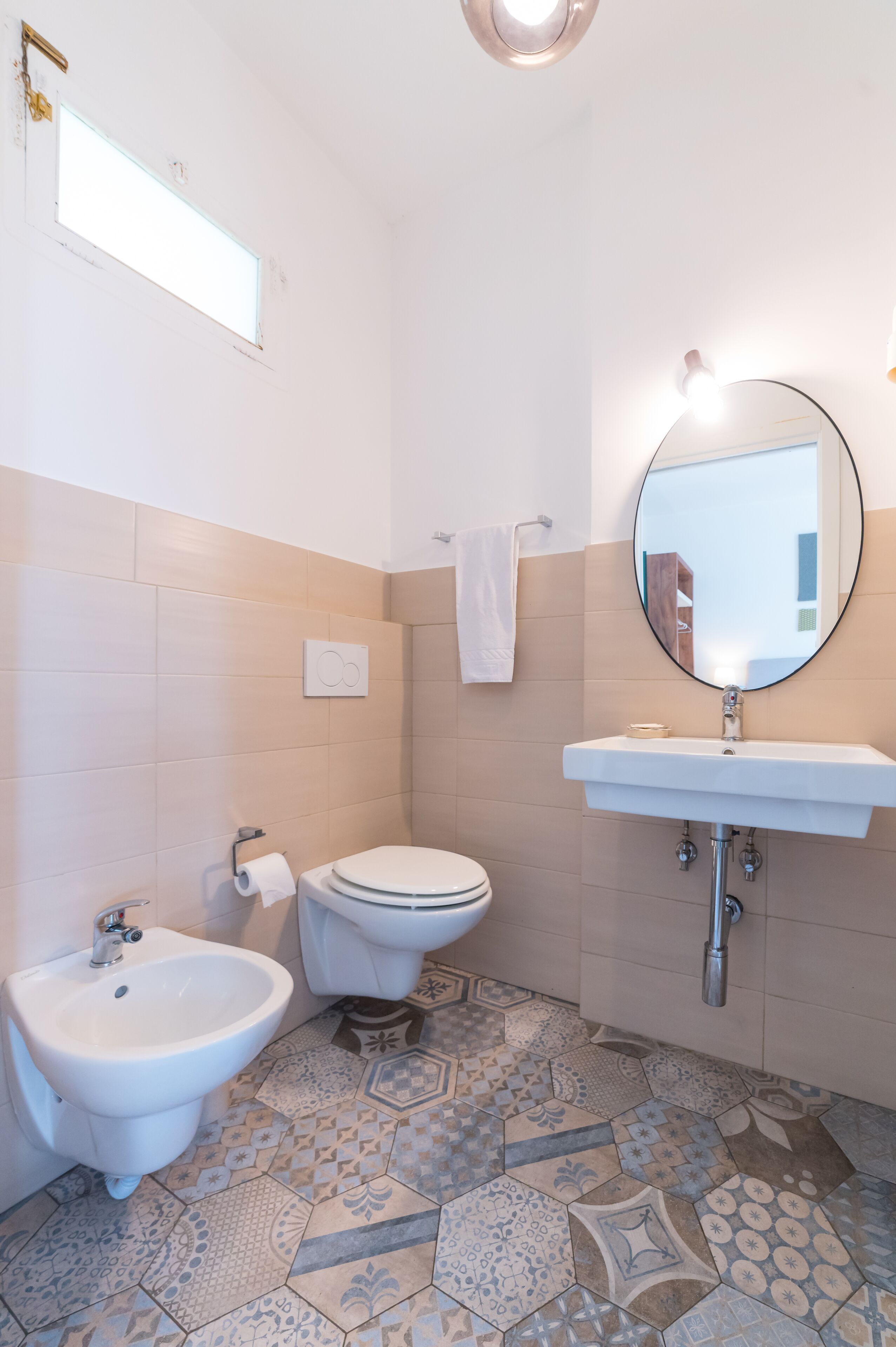 A bathroom with a bidet, toilet, sink, and mirror.